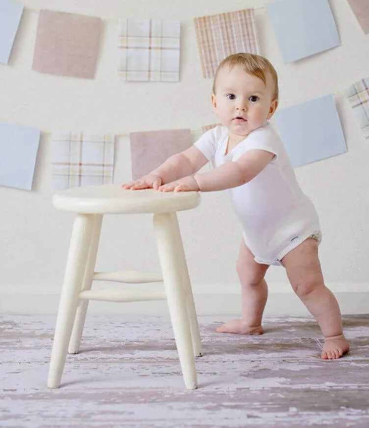 Baby Holding White Wooden Stool